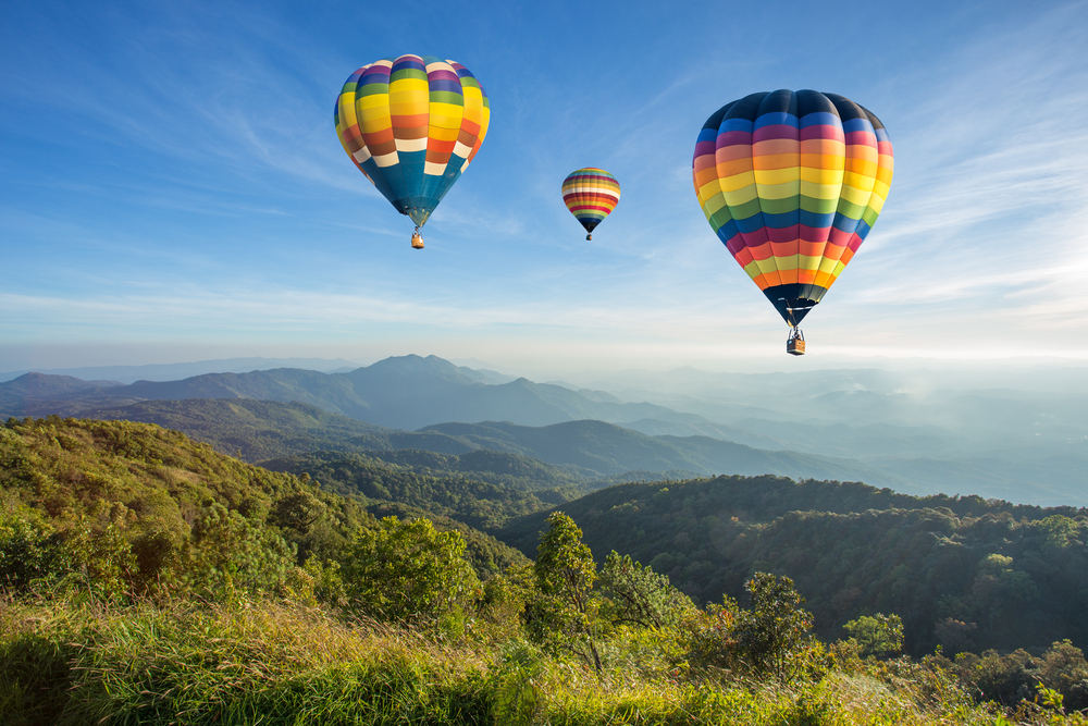 Hot air balloon above high mountain at sunset