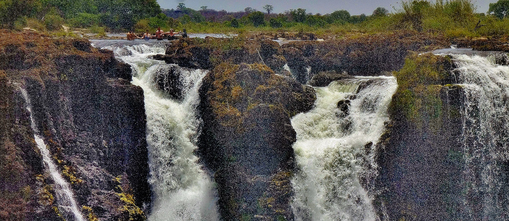 Swimmers in Devil's Pool on the edge of Victoria Falls in Zambia